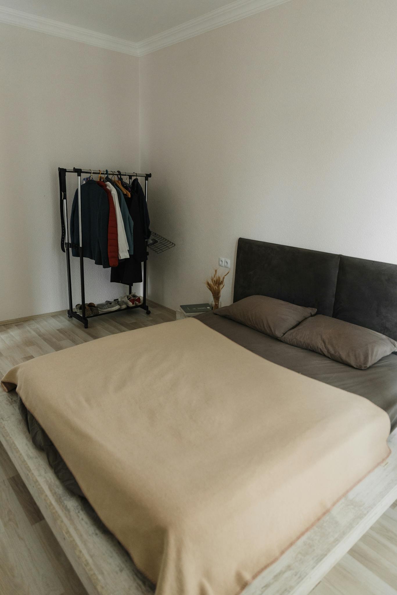 Cozy minimalist bedroom featuring a bed and a clothes rack for a simple living vibe.